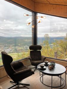 ein Zimmer mit 2 Stühlen und einem Tisch vor einem großen Fenster in der Unterkunft Baugsberget Fjelltopphytter in Alvdal