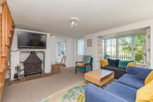 uma sala de estar com um sofá azul e uma lareira em Danny Lodge - Country Cottage Near Brighton by Huluki Sussex Stays em Hurstpierpoint