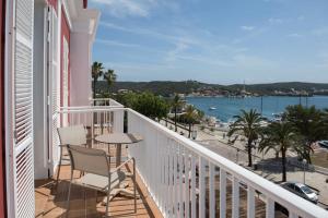 einen Balkon mit einem Tisch und Stühlen sowie Blick auf das Wasser in der Unterkunft Seth Port Mahón in Maó