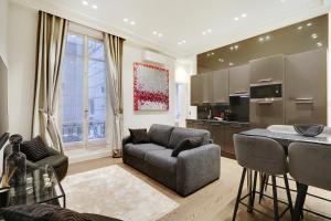 ein Wohnzimmer mit einem Sofa und einer Küche in der Unterkunft Pick A Flat's Apartment in Triangle d'Or - Pierre 1er de Serbie in Paris