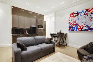 ein Wohnzimmer mit einem Sofa und einer Küche in der Unterkunft Pick A Flat's Apartment in Triangle d'Or - Pierre 1er de Serbie in Paris