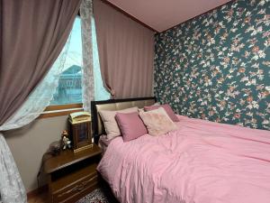 a bedroom with a pink bed and a window at Here and Now Guesthouse - Foreigner Only in Iksan