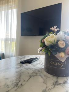 wazon kwiatów na stole z pilotem w obiekcie Dainu street apartament w Szawlach