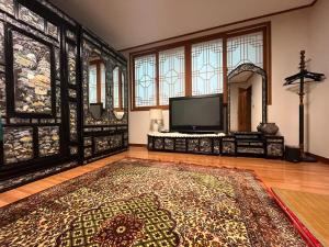 a living room with a television and a rug at Here and Now Guesthouse - Foreigner Only in Iksan