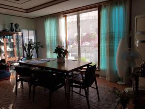 a dining room table with chairs and a large window at Here and Now Guesthouse - Foreigner Only in Iksan