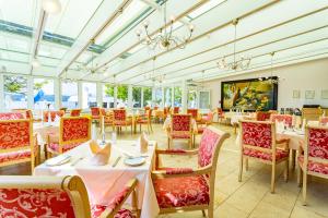 a dining room with tables and chairs and windows at Seehotel Leoni in Berg am Starnberger See