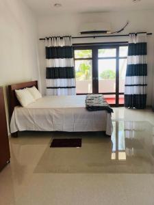 ein Schlafzimmer mit einem Bett und einem großen Fenster in der Unterkunft Hotel Meer in Ambalangoda