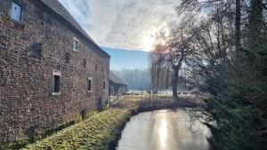 ein Backsteingebäude neben einem Fluss neben einem Gebäude in der Unterkunft Terborgh Budget in Schinnen