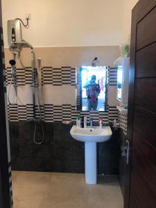 ein Badezimmer mit einem Waschbecken und einer Person im Spiegel in der Unterkunft Hotel Meer in Ambalangoda