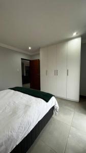 a bedroom with a white bed and white cabinets at Robyns Nest 3 Self Catering Flat in Kloof