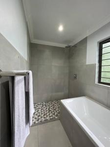 baño blanco con bañera y ventana en Robyns Nest 3 Self Catering Flat en Kloof