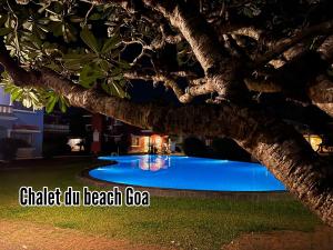 a swimming pool at night under a tree at Villa Marina By The Beach Goa in Benaulim