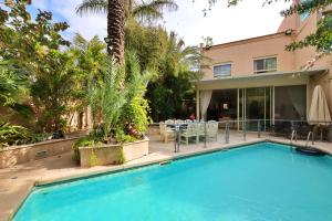 a swimming pool in front of a house with a palm tree at Luxury villa with a heated pool, Jakuzi and a sea view 70m from the beach in Herzliya