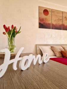 a sign that reads home in a bedroom with a vase of flowers at TraMonti Apartments in Poggio Picenze