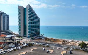 a tall building with a parking lot next to the ocean at Luxury villa with a heated pool, Jakuzi and a sea view 70m from the beach in Herzliya