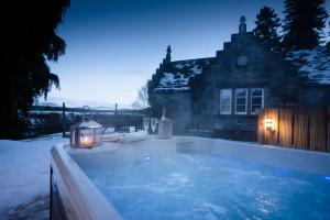 a jacuzzi tub with two candles in the snow at West Lodge - Seasgair Lodges in Kincraig