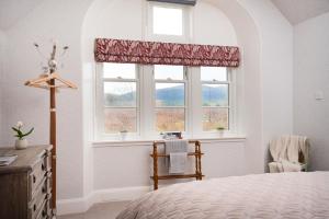 a bedroom with a bed and a window and a chair at West Lodge - Seasgair Lodges in Kincraig