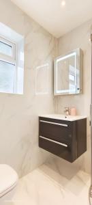 W łazience znajduje się umywalka, lustro i toaleta. w obiekcie Green Garden in Northwest London w Londynie