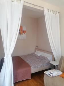 een slaapkamer met een bed met witte gordijnen bij Natalija Twister Apartment in Budva