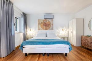biała sypialnia z dużym łóżkiem i niebieskim kocem w obiekcie Vasari Apartment we Florencji
