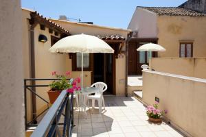 a balcony with an umbrella and a table and chairs at Residence Cortile Mercè in Trapani