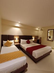 a hotel room with two beds and a mirror at Hotel West INN-Near Mumbai International Airport in Mumbai