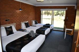 a room with three beds and a brick wall at Berrigan Motel in Berrigan