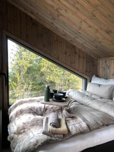 a bed in a room with a large window at Baugsberget Fjelltopphytter in Alvdal