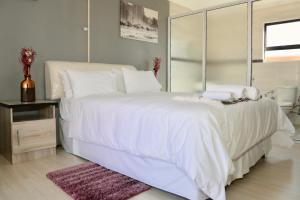 een wit bed met witte lakens en kussens erop bij Joy Guest House, Mabote in Maseru