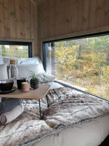 a room with a bed with a table and a large window at Baugsberget Fjelltopphytter in Alvdal