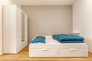 Una cama blanca con almohadas azules encima. en Monolocale open space, en Legnano