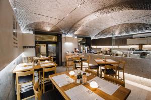 Un restaurante con mesas y sillas de madera y una cocina. en Eat IT cozy downtown apartments, en Oradea