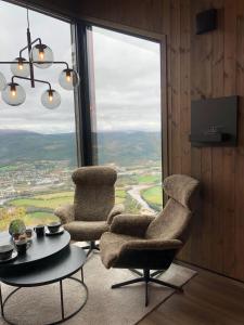 ein Wohnzimmer mit 2 Stühlen, einem Tisch und einem großen Fenster in der Unterkunft Baugsberget Fjelltopphytter in Alvdal