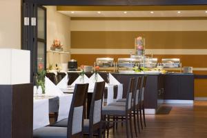 a dining room with tables and chairs and a bar at IntercityHotel Hamburg Hauptbahnhof in Hamburg