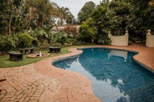 une piscine entourée d'un chemin en briques dans l'établissement Amanzi Lodge, à Harare