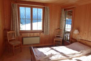 a bedroom with a bed and two chairs and a window at Ferienhaus Bensel in Alvaneu