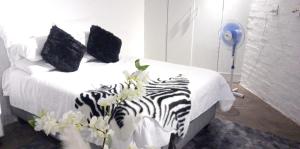 een slaapkamer met een bed met zwarte en witte lakens bij Chic Urban Maboneng Getaway, Free Wi-Fi in Johannesburg