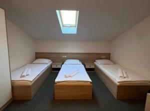 two beds in a small room with a window at Motel Papić in Tomislavgrad