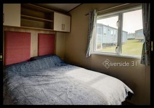 a small bedroom with a bed and a window at 3 bedroom home on a Haven holiday park in Allhallows