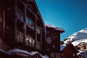 a building in the snow with a mountain in the background at Le Fitz Roy, a Beaumier hotel in Val Thorens