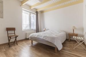 a white bedroom with a bed and a window at Jolie maison et sa véranda pour de belles vacances in Saint-Philibert