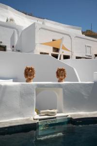 a white house with a pool of water at Madame Kalitsi Cozy Suites in Fira