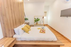1 dormitorio con 1 cama grande con sábanas blancas y almohadas amarillas en The Morris Dalat Hotel en Da Lat