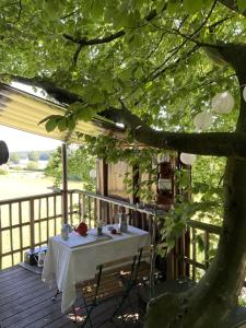 a table and chairs on a deck with a tree at Treehouse escape in Kværndrup