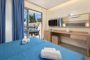a hotel room with a blue bed and a television at Marathon Hotel - All Inclusive in Kolymbia
