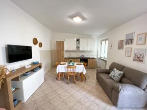 sala de estar con mesa, sofá y cocina en NaturAmare Apartments Palinuro, en Palinuro