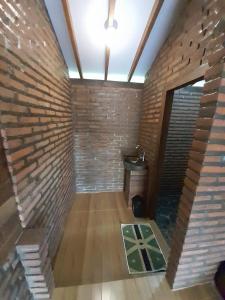 Avrila Ijen Guest House في Licin: غرفة فارغة بحائط من الطوب ودورة مياه