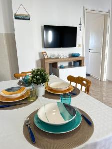 una mesa de comedor con platos y utensilios. en NaturAmare Apartments Palinuro, en Palinuro