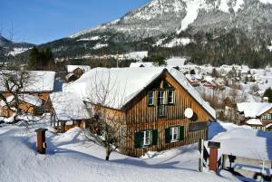 ein Holzhaus im Schnee mit einem Berg in der Unterkunft Ferienhaus Archkogl in Grundlsee
