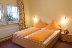 a bedroom with a bed with orange sheets and a window at Gästehaus Aladin in Cochem